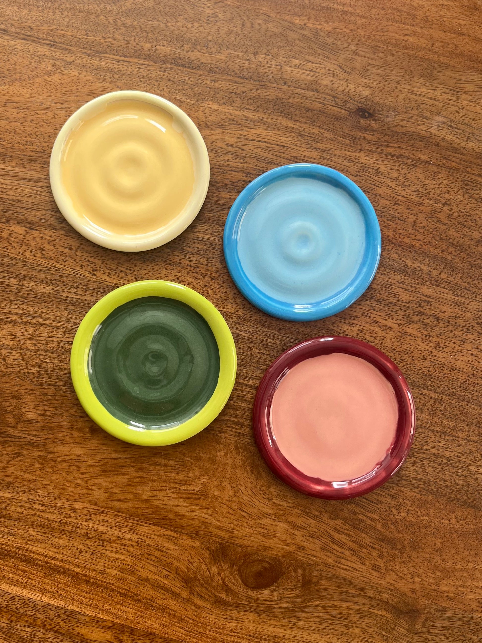 a group of colourful ceramic coasters on a wooden table